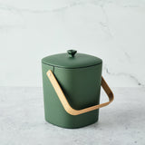 Green Astrik Compost Bin with a wooden handle on a light gray background