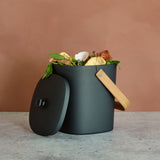 Dark gray Astrik Compost Bin with a wooden handle on a neutral background