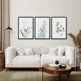 Modern living room with a white sofa, wooden coffee table, and framed Watercolor Botanical Set of 3 Prints Wall Decor on the wall.