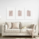 Beige sofa with decorative pillows and a blanket, featuring Blush Pink Botanical Line Art Print Set of 3 on the wall.