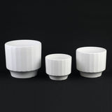 3-Piece White Stoneware Planter Set with Fluted Design of different sizes on a black background