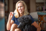 Woman holding VANILLA SWIRL LUXURY LIP BUTTER™ - THE APPALACHIAN GOAT with a dog sitting next to her in a home setting