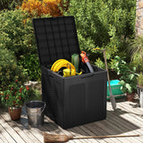 Black garden storage box on a wooden deck with gardening tools inside, surrounded by plants.