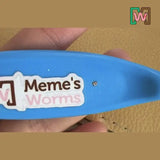 Blue Worm Comb with 'Meme's Worms' label held by a hand against a brown background