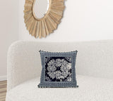 Decorative pillow with floral pattern on a white sofa, with a wooden mirror in the background.