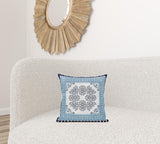 Decorative pillow with blue and white pattern on a beige sofa, with a wooden mirror in the background.