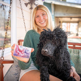 Woman holding a POMEGRANATE GOAT'S MILK SOAP SLICE 5 oz. with a black dog sitting on her lap on a porch.