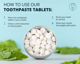 Instructional graphic showing a metal tin of white toothpaste tablets on a light blue background with mint leaves. Text reads 'HOW TO USE OUR TOOTHPASTE TABLETS:' and lists four steps, including placing one tablet in the mouth, chewing it into a creamy paste, brushing teeth normally, and rinsing with water.