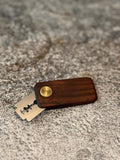 Wooden case with a gold button and a metal blade on a textured surface