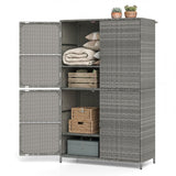A gray wicker-finish storage cabinet with two doors open, showing shelves with folded blankets, pillows, wooden crates, a wicker basket, and a gray storage box. Two small potted succulents sit on top.