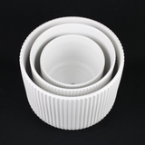 Set of three white ceramic bowls with ribbed texture on a black background