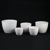 Set of white ceramic pots on a black background 5-Piece White Plastic Planter Pot Set – Modern Round Design