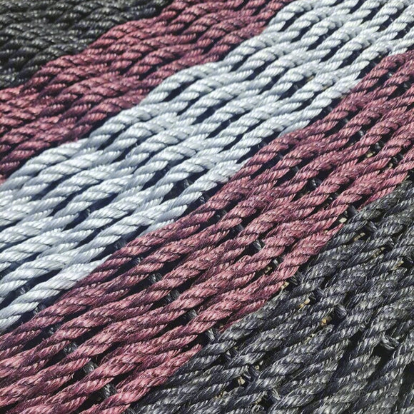Close-up of woven fabric with pink, blue, and gray stripes on a neutral background