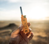Hand holding a small orange device with a bear logo against a blurred natural background