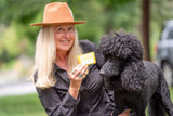 Woman holding a black dog and CHAMOMILE + LEMON SOAP SLICE 5 oz. outdoors.