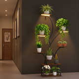 Decorative indoor plant stand with multiple potted plants against a dark wall.