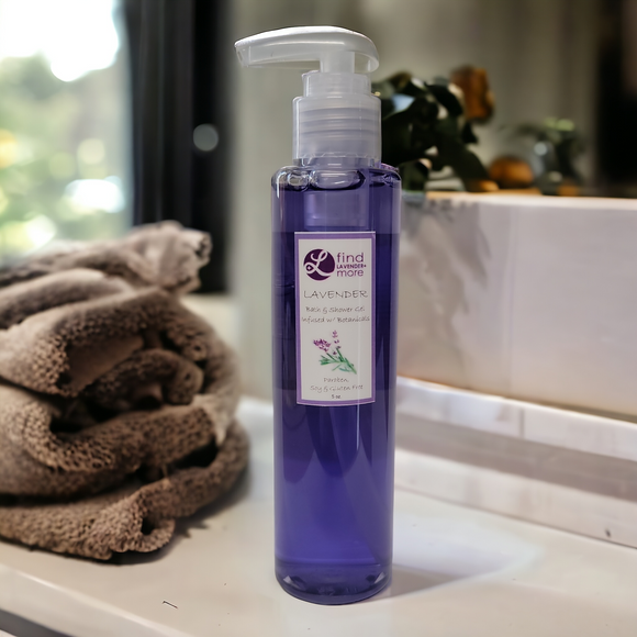 Purple bottle of lavender product on a bathroom counter with towels and a mirror in the background.