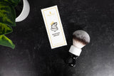 Shaving brush with packaging on a dark surface