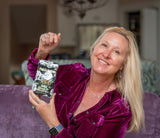 Woman in a purple velvet jacket holding a product package in a home setting