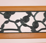 Decorative metal wall art with floral patterns and wooden frame on a plain background