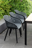 Black chairs with gray seats arranged around a table outdoors.
