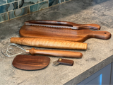 Set of wooden kitchen utensils including a spatula, cutting boards, and a knife on a countertop.