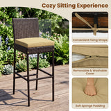 Outdoor bar stool with a dark brown woven frame and a beige seat cushion, shown on a wooden deck with a garden background. The right side includes three feature callouts: convenient fixing straps, a removable and washable cover, and soft sponge padding.