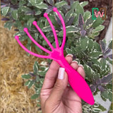 Hand holding a Worm Comb against a plant background