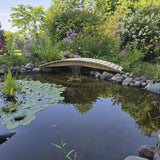 Pond with a wooden bridge surrounded by lush greenery and flowers
