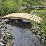 Wooden bridge over a small pond in a garden setting with rocks and plants.