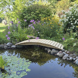 Small wooden bridge over a pond in a garden with flowers and trees.