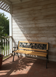 Wooden bench with decorative metal backrest on a wooden porch