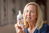 Woman holding a bottle of HONEYSUCKLE GOATS MILK LOTION