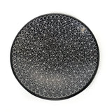 Round black plate with white geometric pattern on a white background
