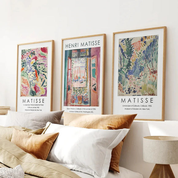 Framed Henri Matisse art prints on a wall above a sofa with pillows.