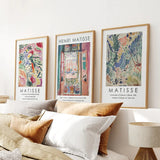 Framed Henri Matisse art prints on a wall above a sofa with pillows.