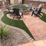 Outdoor patio with Adirondack chairs around a fire pit, featuring a brick pathway and grassy area.