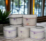 Five jars of body butter with visible labels on a wooden surface.