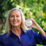 Woman holding a container of LAVENDER THYME ARNICA SOUFFLÈ 8 oz. outdoors
