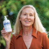 Woman holding a bottle labeled 'A Bottle of Good Things' against a green outdoor background
