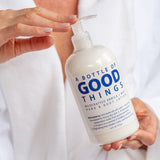 Hand holding a bottle of 'A Bottle of Good Things' lotion with a white background