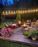 Backyard evening scene with string lights, fire pit, Border White Sand Outdoor Rug, and outdoor furniture.