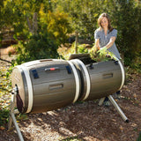 Person using a large cylindrical compost bin outdoors.