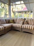 Striped outdoor sofa on a Basic Cream & Brown patio rug with a view of trees and another house.
