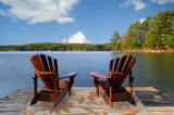 Two wooden Adirondack chairs on a dock overlooking a lake with trees and a clear blue sky. Bellingrath Salmon
