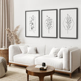 Modern living room with a white sofa, wooden coffee table, and Minimal Flower Line Art: Black White Wall Art Set on the wall.