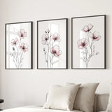Three framed floral prints on a wall above a sofa.