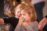 Two young children sitting together, one holding a COCONUT LIME VERBENA SOAP SLICE 5.5 oz.