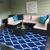 Outdoor patio with sectional sofa, blue cushions, and a coffee table on a blue patterned rug.