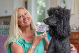 Woman holding a LAVENDER GOAT'S MILK SOAP SLICE 5 oz. with a black dog looking at it